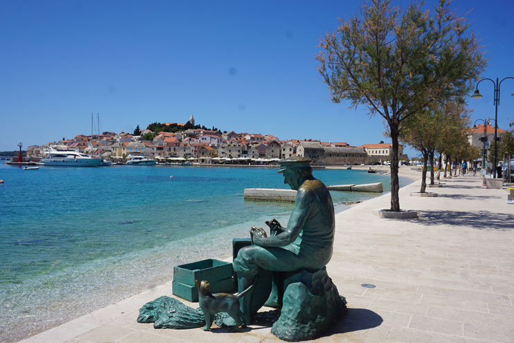 Estatua del pescador con puerto de fondo primosten
